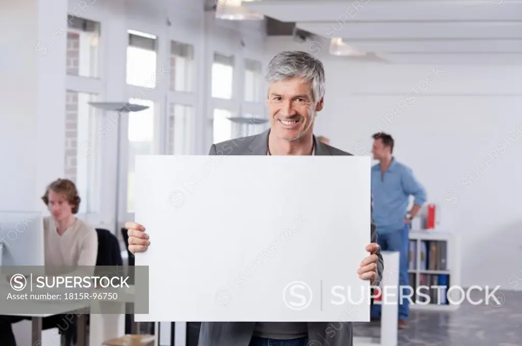 Germany, Bavaria, Munich, Mature man holding placard in office