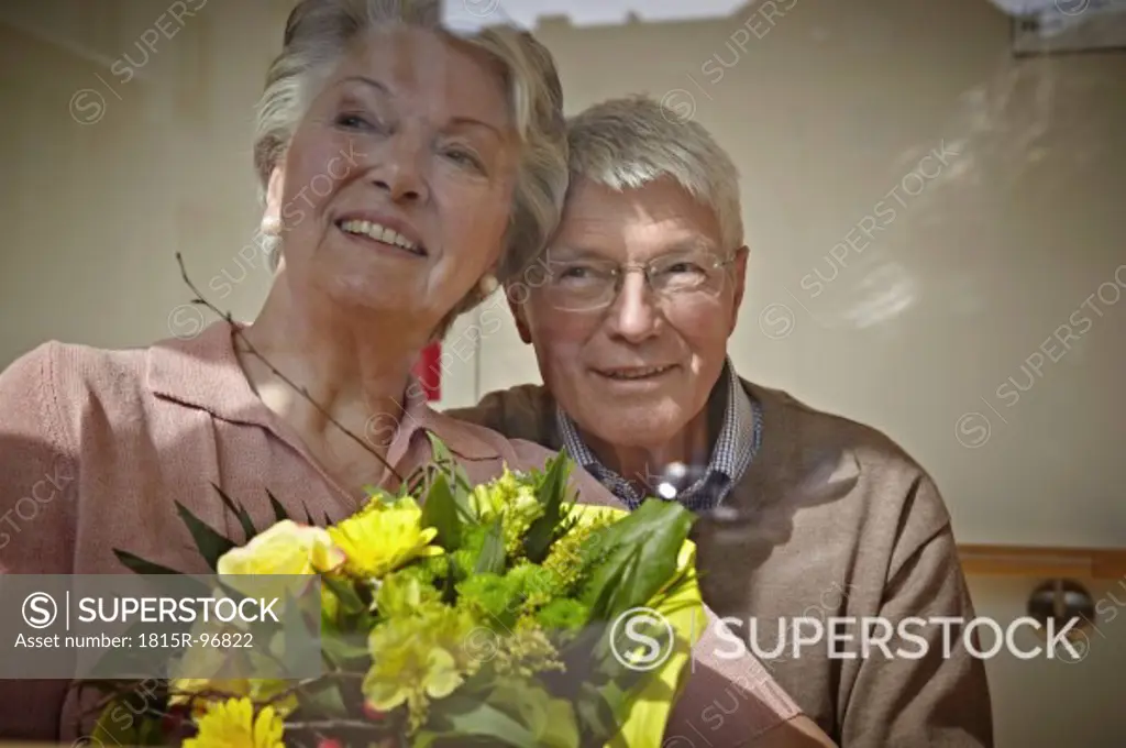 Germany, Cologne, Senior couple with flower bouquet, smiling