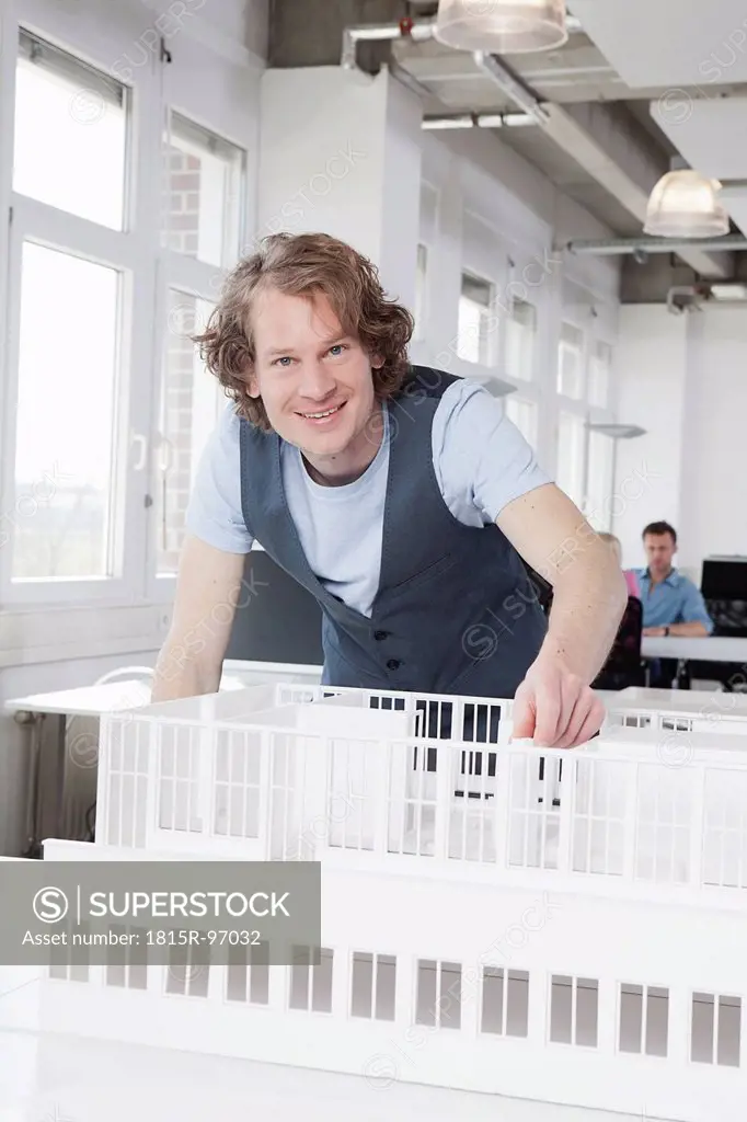 Germany, Bavaria, Munich, Architect with architectural model, colleagues working in background