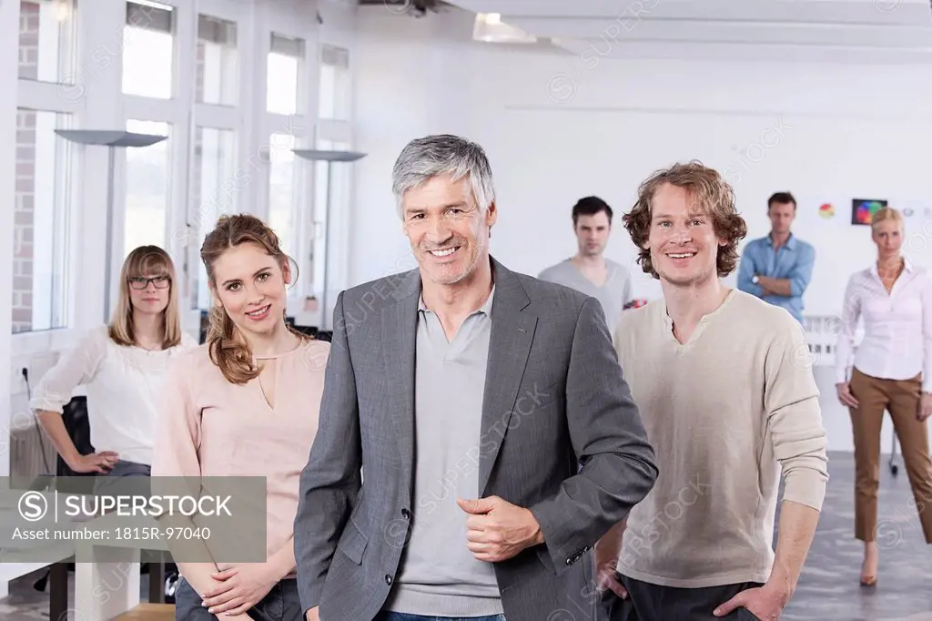 Germany, Bavaria, Munich, Mature man with colleagues standing in office, smiling