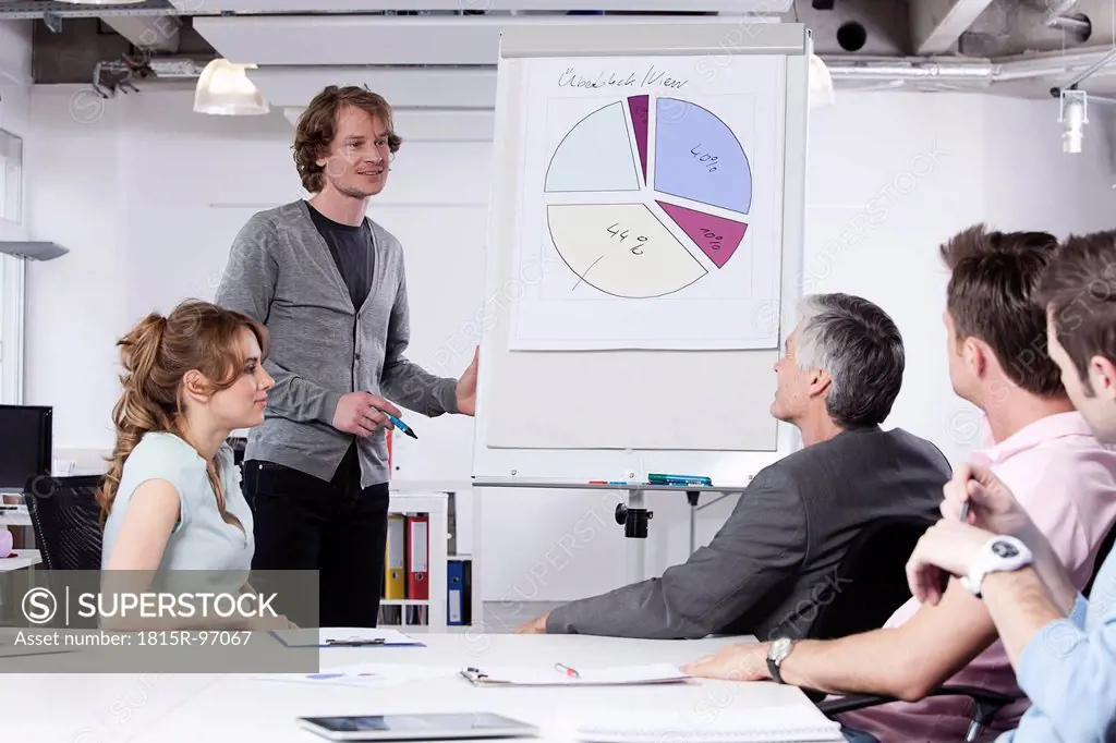 Germany, Bavaria, Munich, Man explaining pie chart to colleagues