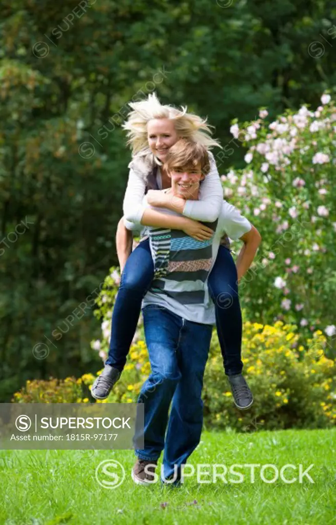 Austria, Young man giving piggy back ride to woman