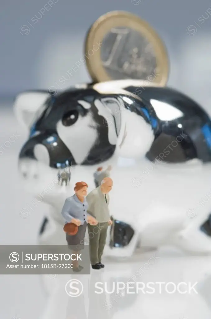 Senior couple figurines besides piggy bank with euro coin