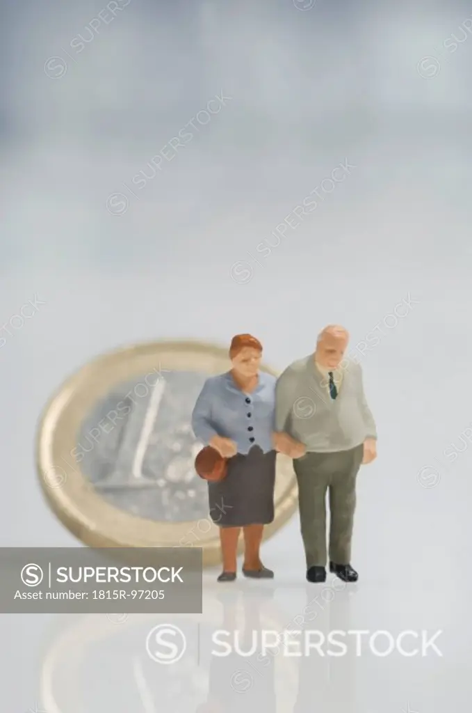 Senior couple figurines in front of euro coin