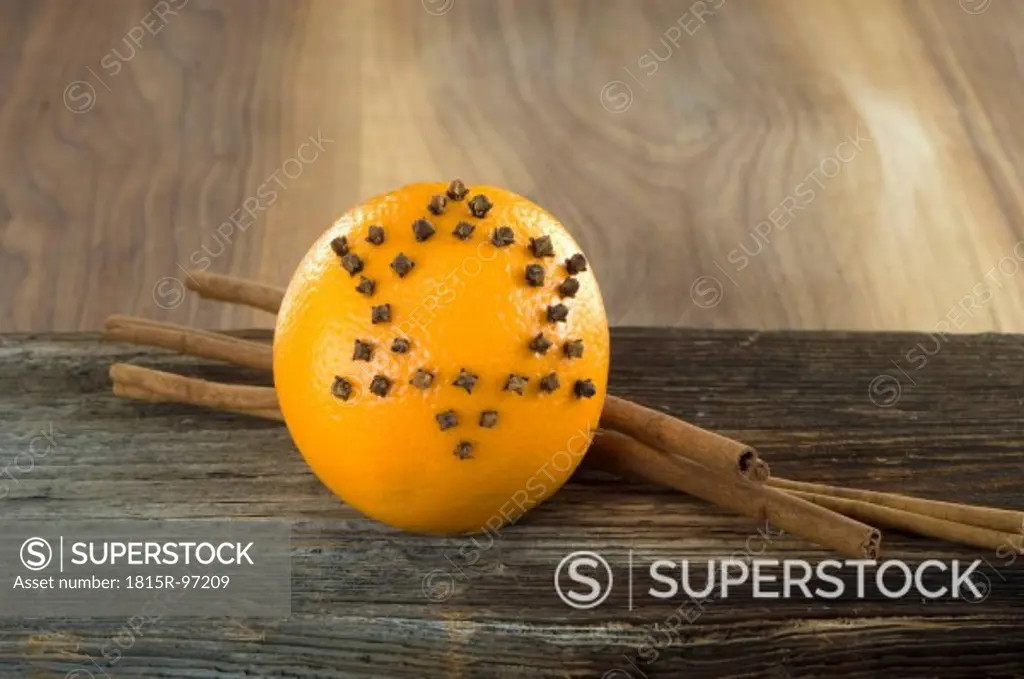 Orange studded with cloves and cinnamon stick on table, close up