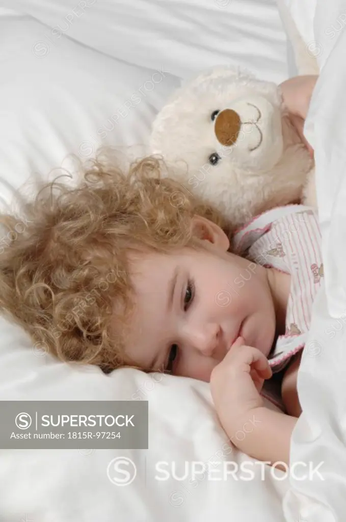 Sick girl lying in bed with teddy bear