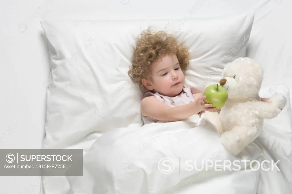Girl feeding apple to teddy bear