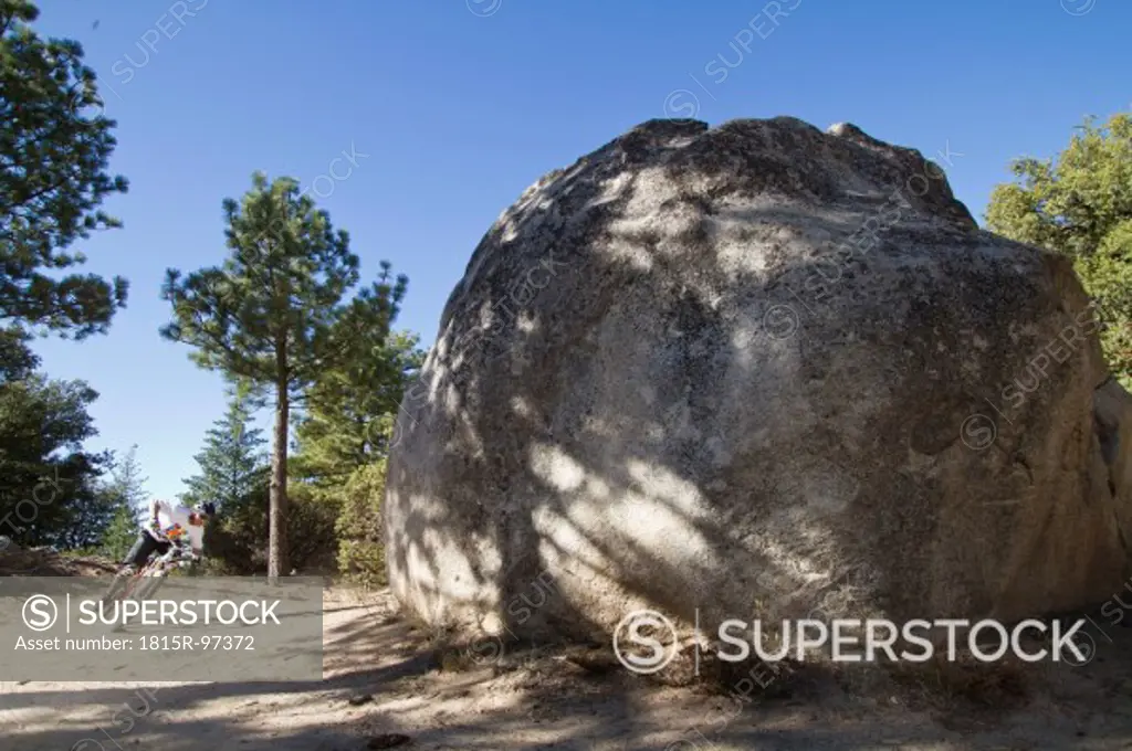 USA, California, Mountain biker cycling by boulder