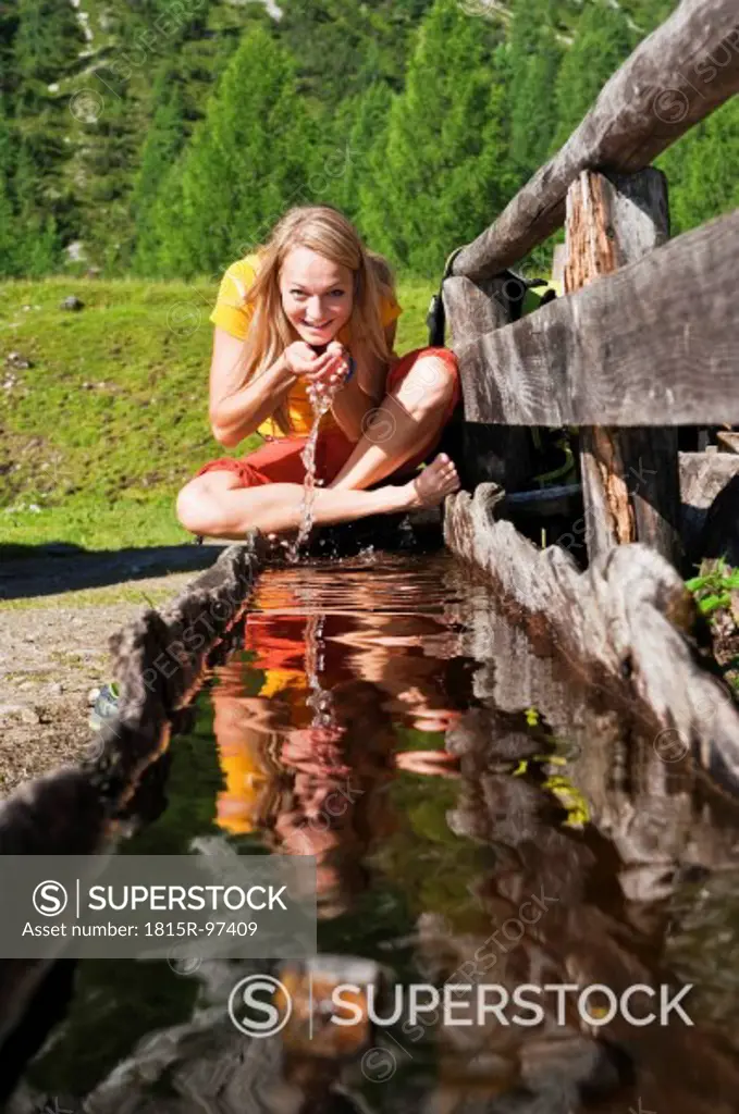 Austria, Salzburg County, Young woman drinking water from water trough, portrait