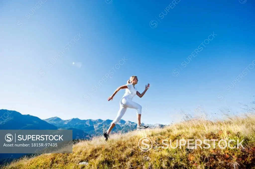 Austria, Salzburg County, Young woman running in alpine meadow
