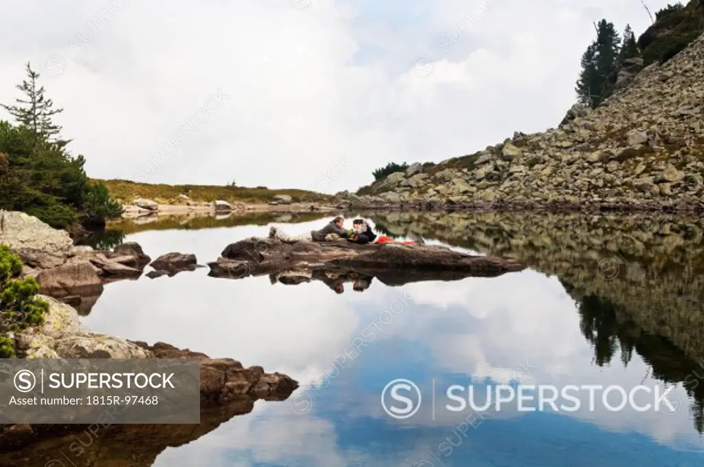 Austria, Styria, Man and woman lying on rock at Lake Spiegelsee