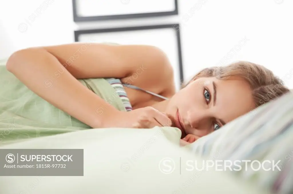 Germany, Bavaria, Young woman on bed, portrait