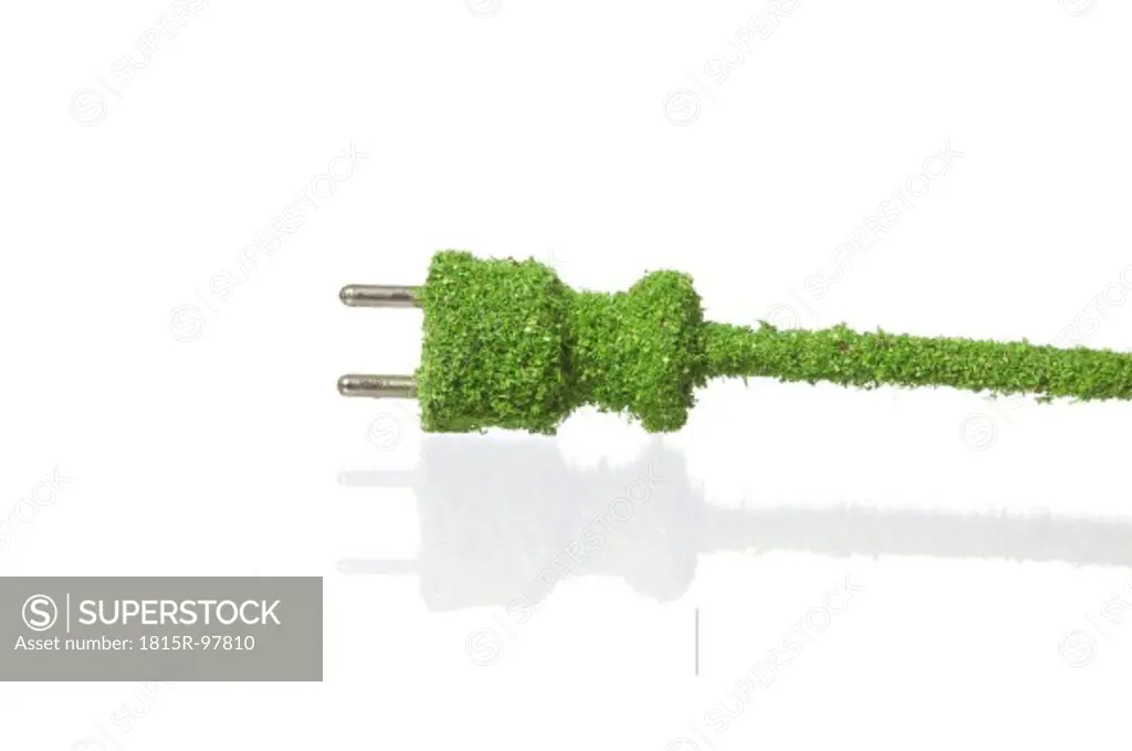 Electric plug covered with grass on white background