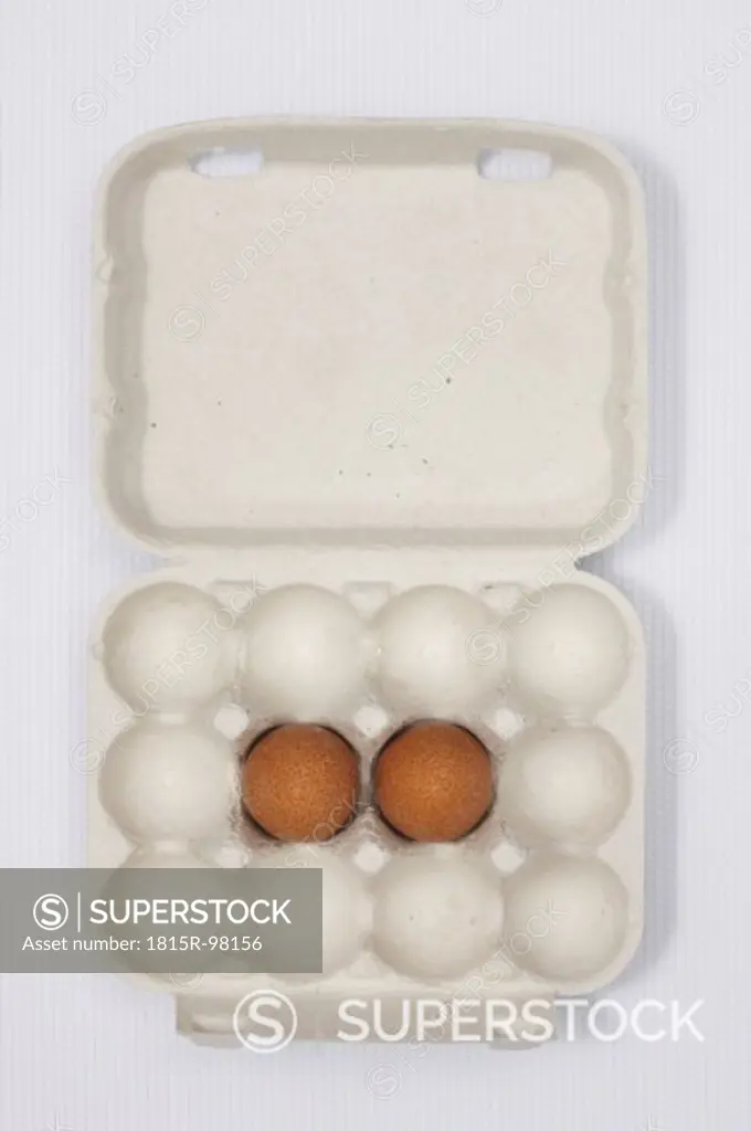 Two brown eggs in carton