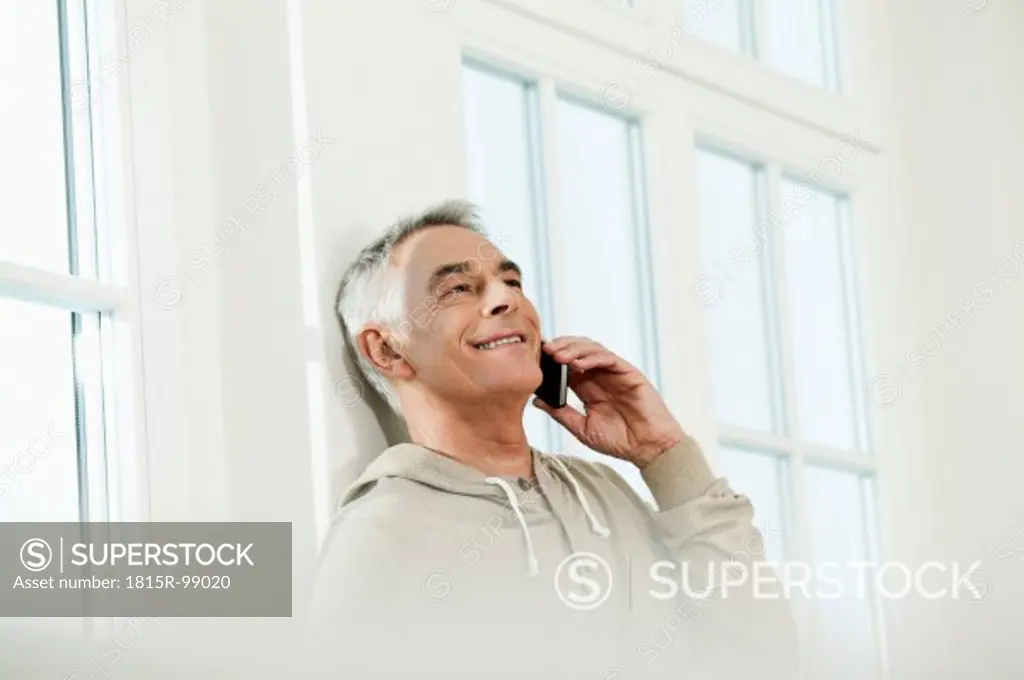 Germany, Berlin, Senior man using cell phone, smiling