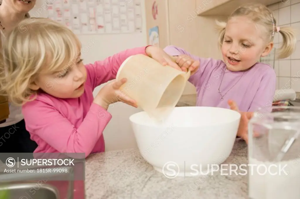 Sisters making cake in kitchen