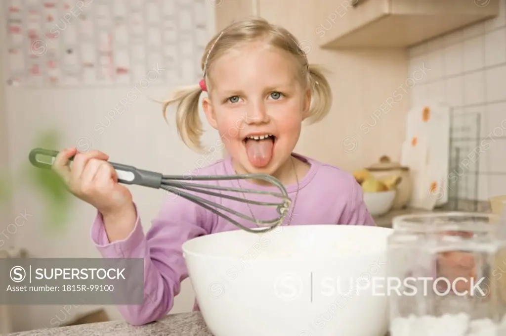 Girl licking whisk covered with batter