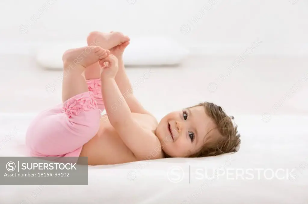 Baby girl lying on back, smiling, portrait