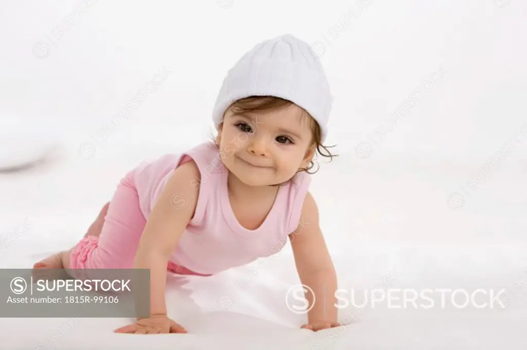 Baby girl crawling on baby blanket, smiling
