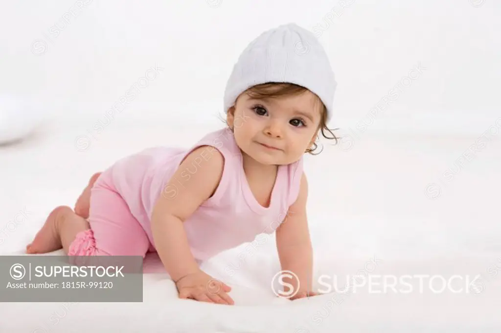 Baby girl crawling on baby blanket, smiling