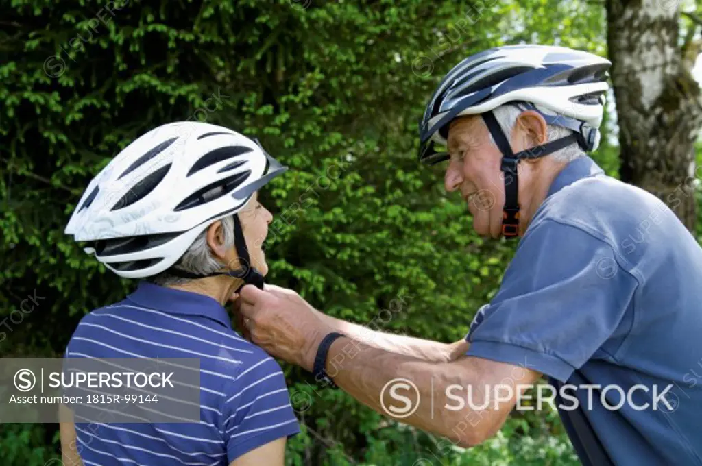 Germany, Bavaria, Senior couple with bicycle helmet, smiling