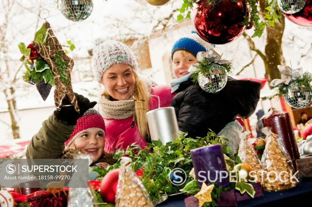 Austria, Salzburg, Mother with children at christmas market, smiling