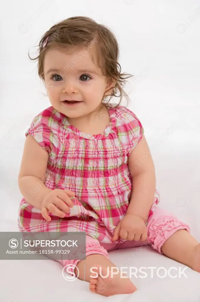 Baby girl sitting on baby blanket, smiling