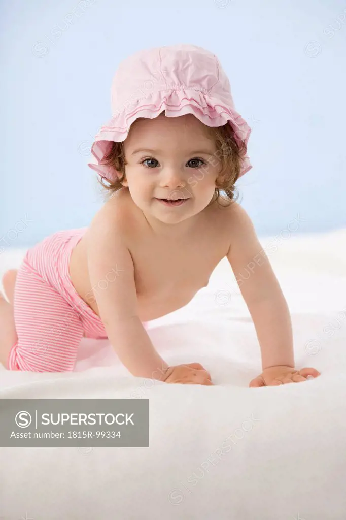 Baby girl crawling on blanket, smiling