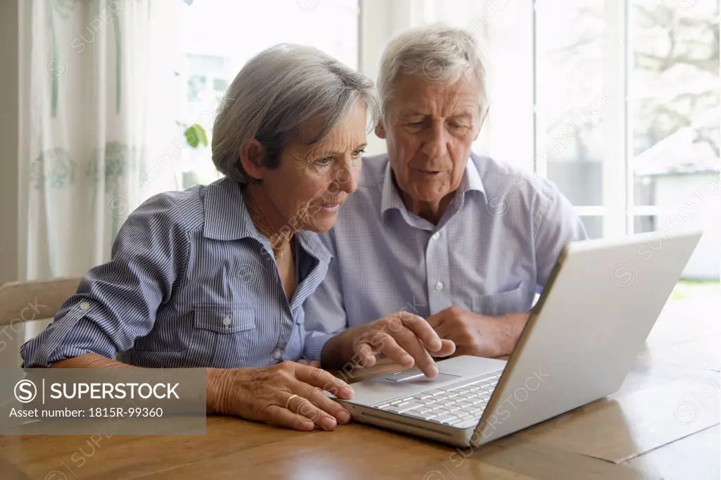 Germany, Bavaria, Senior couple using laptop at home