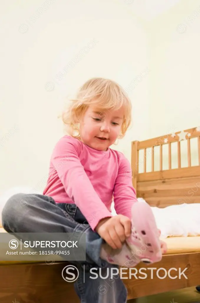 Girl siting on bed and putting shoes