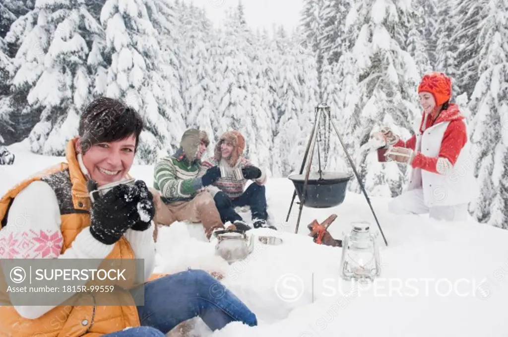 Austria, Salzburg, Men and women sitting at fire place in winter