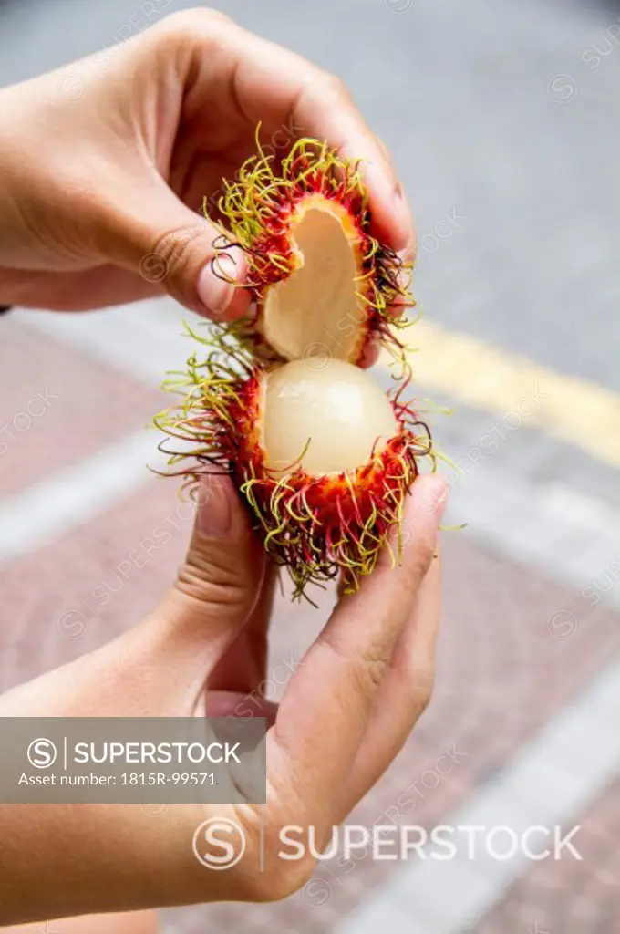 Malaysia, Woman opening rambutan fruit, close up