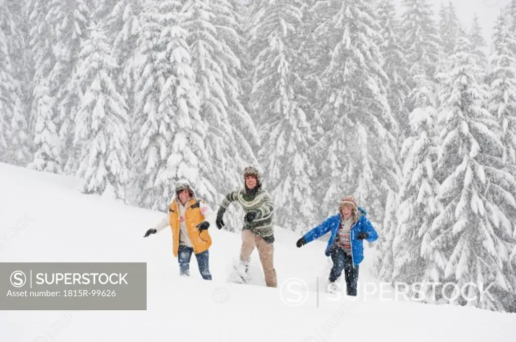 Austria, Salzburg, Men and woman walking through winter landscape