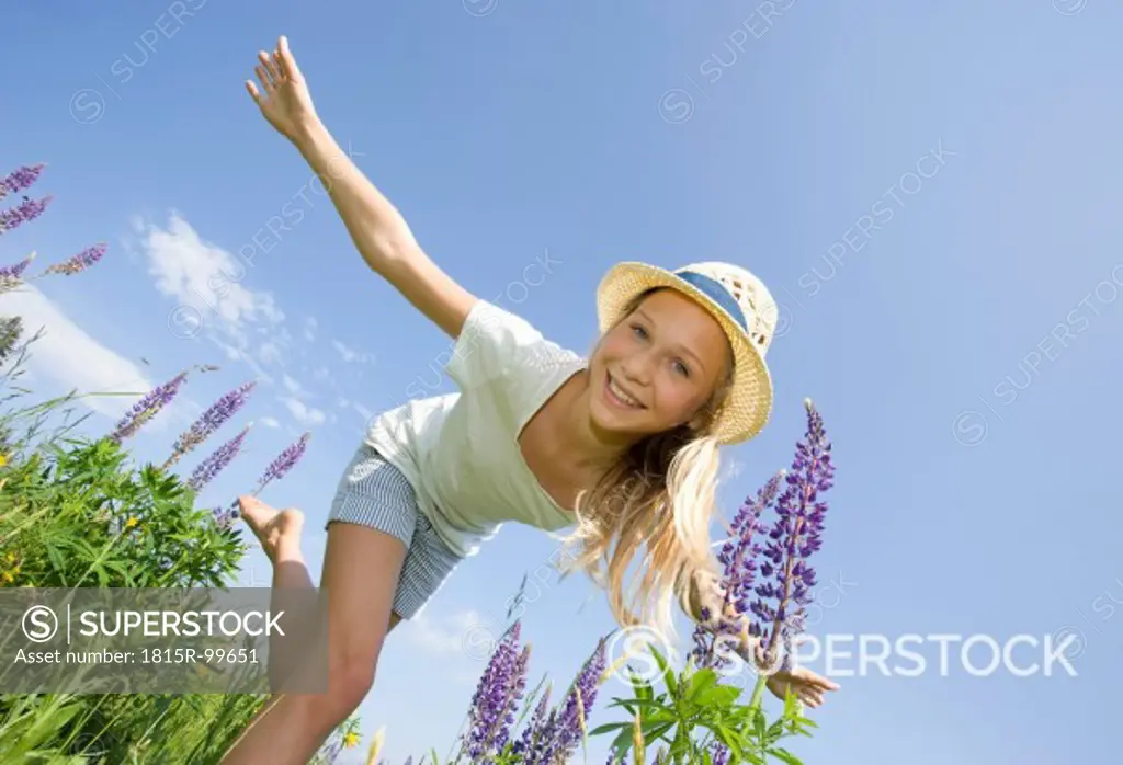 Austria, Teenage girl doing gymnastics in field, smiling, portrait