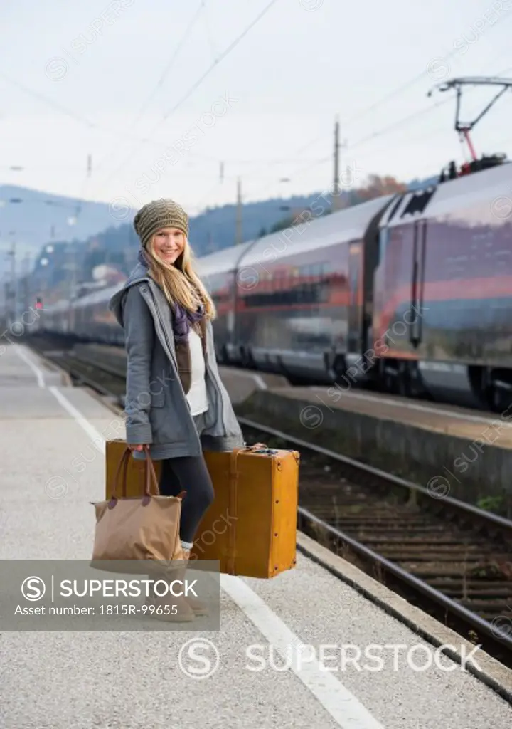 Austria, Teenage girl with suitcase on train station