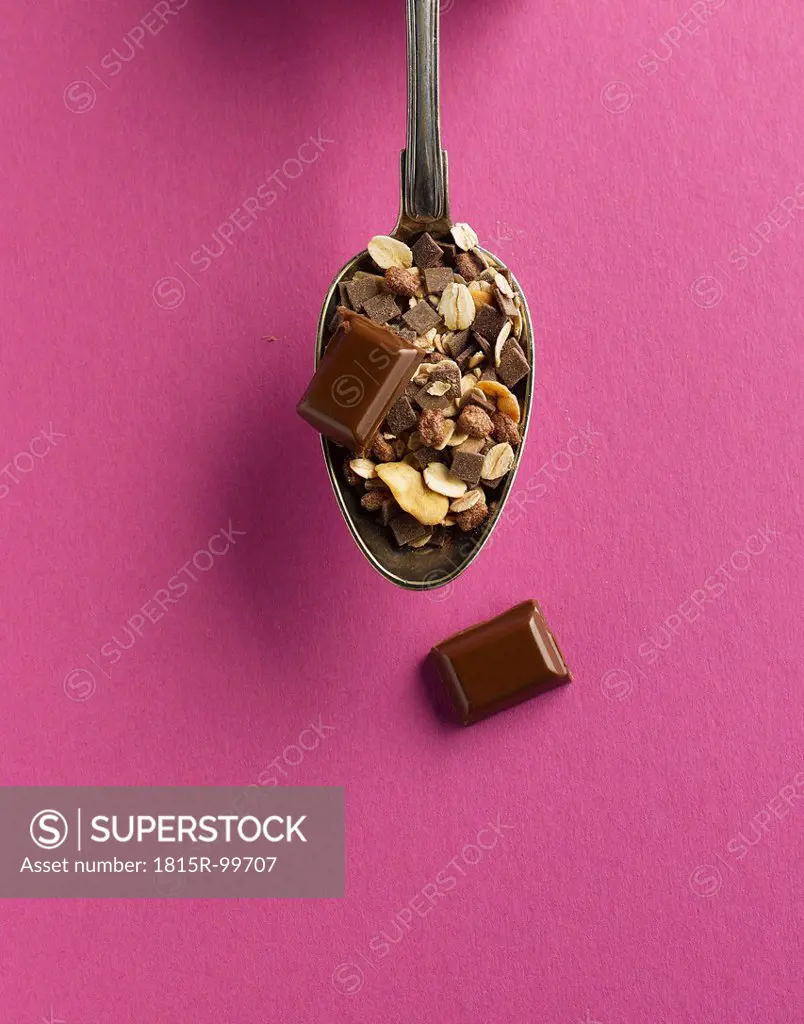 Cereal and chocolate in spoon on pink background