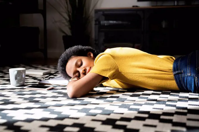 Young woman lying on the floor at home with closed eyes