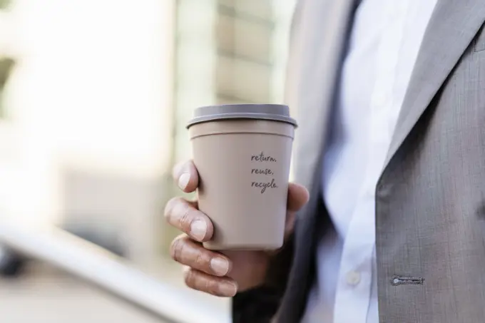 Close-up of businessman holding reusable takeaway coffee cup