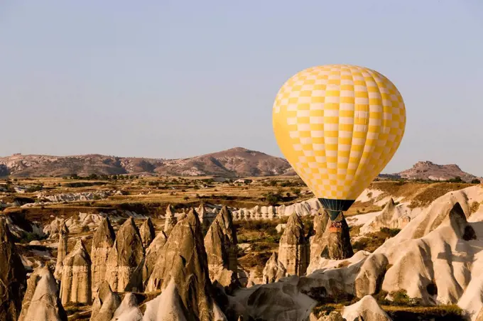 Yellow hot air balloon flying at Goreme National Park, Cappadocia, Turkey