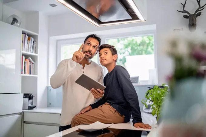 Father and son using tablet in kitchen