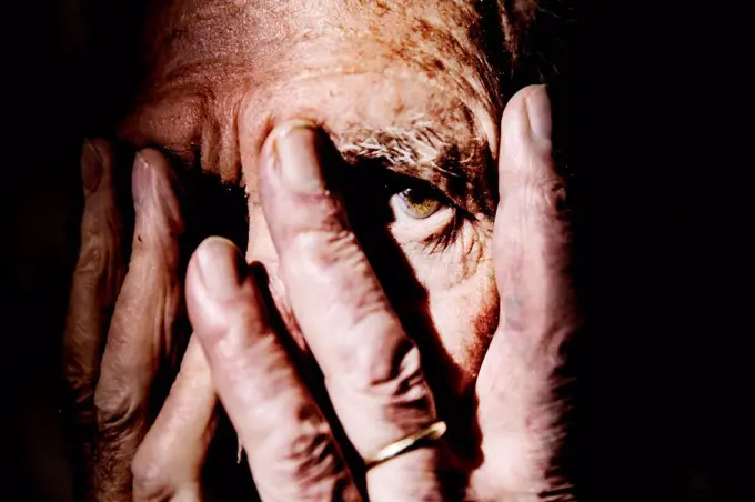 Senior man covering face with hands, close-up