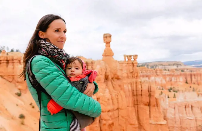 Woman carrying her daughter in a baby carrier at hoodoos in Bryce Canyon, Utah, USA