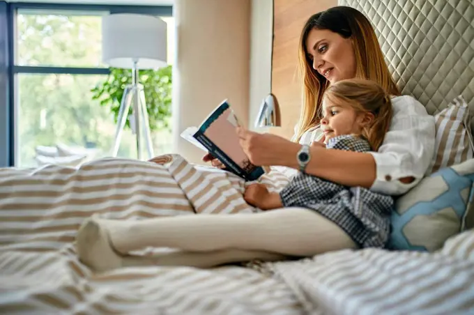Mother and daughhter reading a book in bed