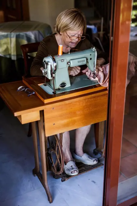 Senior woman using an sewing old machine at home