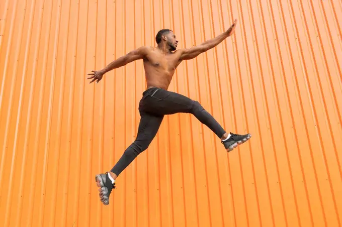 Athlete jumping in front of an orange wall
