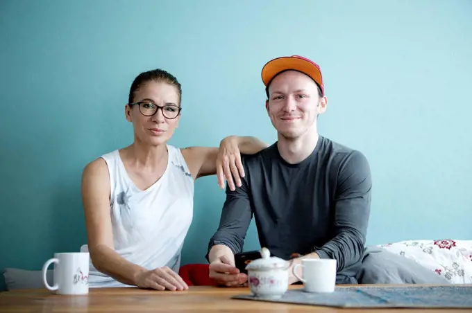 Mother and son sitting at the kitchen table, drinking coffee