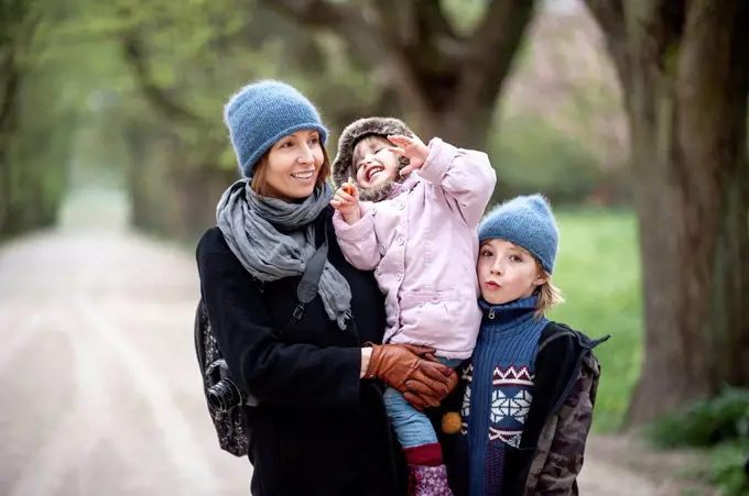 Portrait of happy mother with son and little daughter in a park