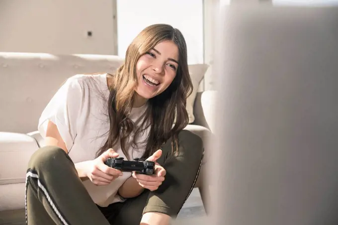 Happy young woman playing video game at home