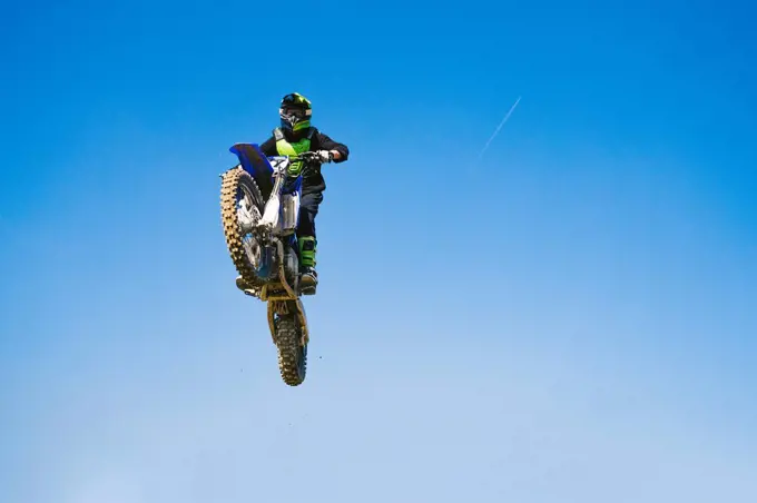 Motocross driver jumping in blue sky
