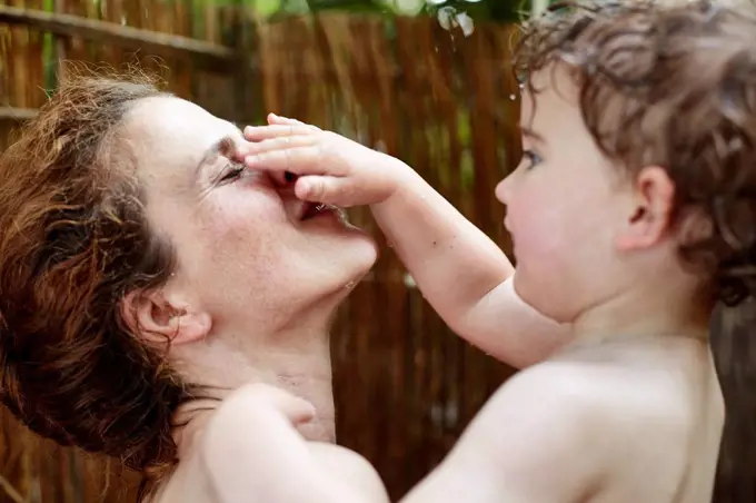 Mother and little daughter taking a shower outdoors having fun
